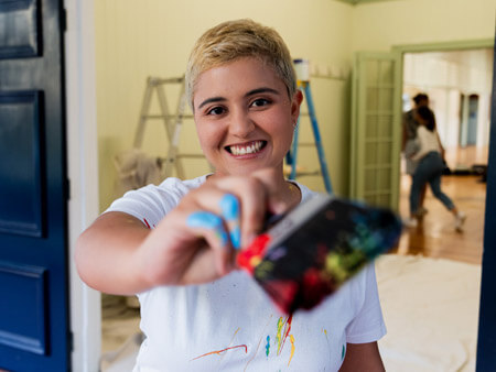 Photo of woman with short hair smiling with holding a large paint brush