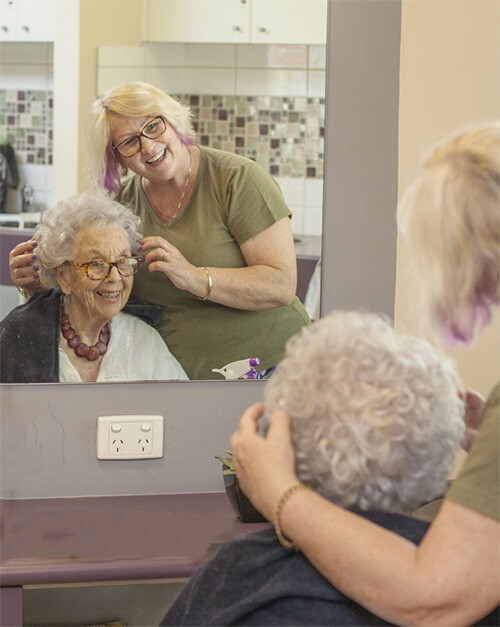 Photo of hairdresser giving senior a haircut