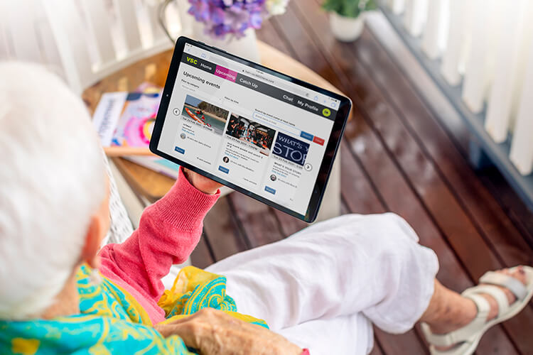 Senior holding tablet with Virtual Social Centre home page