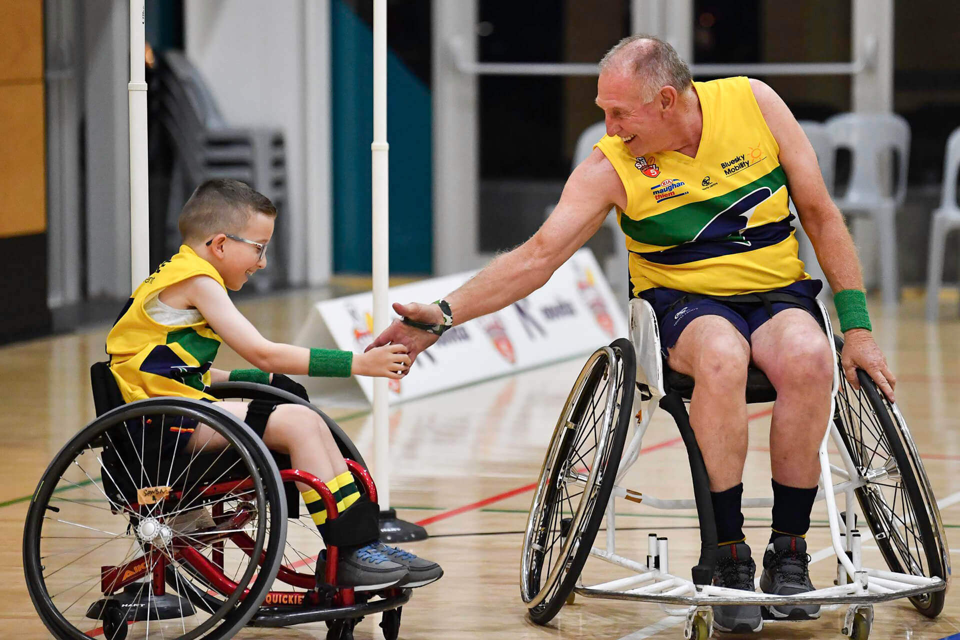 Young boy and man in wheelchairs shaking hands